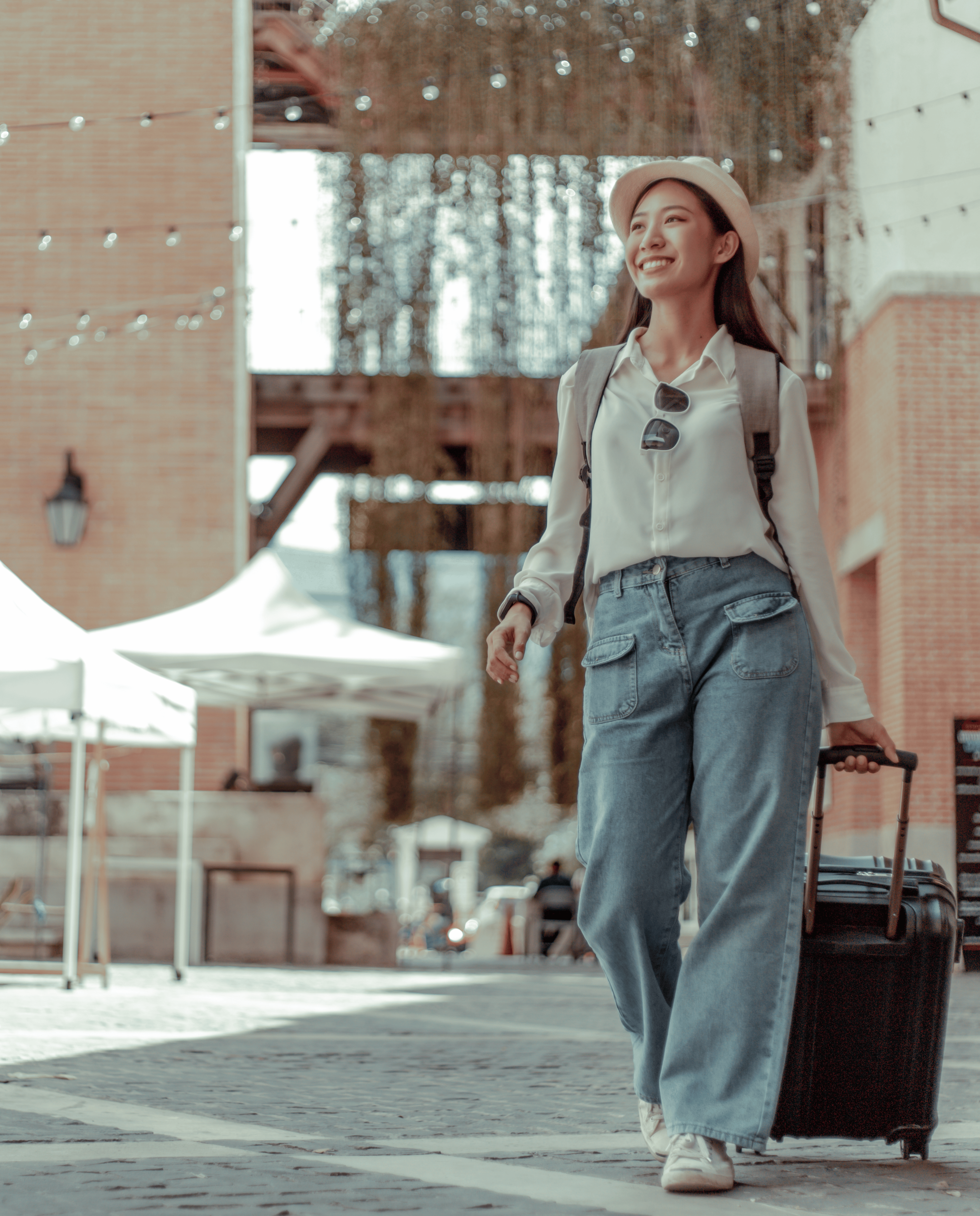 Woman traveler rolling a suite case through a street.
